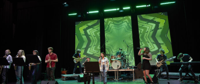 Singers standing on a stage with green light screen behind them