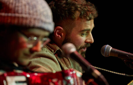 Two performers singing into a microphone