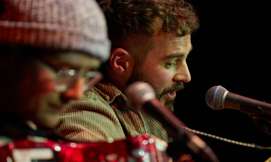 Two performers singing into a microphone
