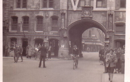 Old black and white photograph depicting the Guildhall curing VE celebrations. The Guildhall building has a big VE sign hung across its central windows with people walking through its arches.